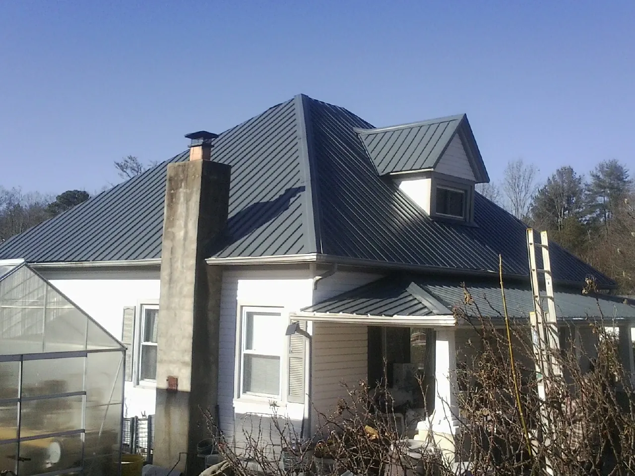 Dark blue standing seam metal roof on a white farmhouse with dormer — Slate & Tile Roof Repair by Roofing Brothers in Amanda Park