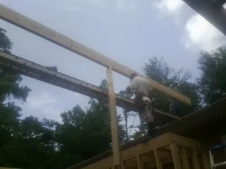 Carpenter setting a ridge beam over a new addition frame — Ice Dam Removal by Roofing Brothers in Amanda Park