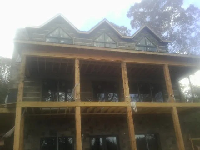 Dormers and porch framing on a large log home under construction — Roof Coating work by our crew in Amanda Park