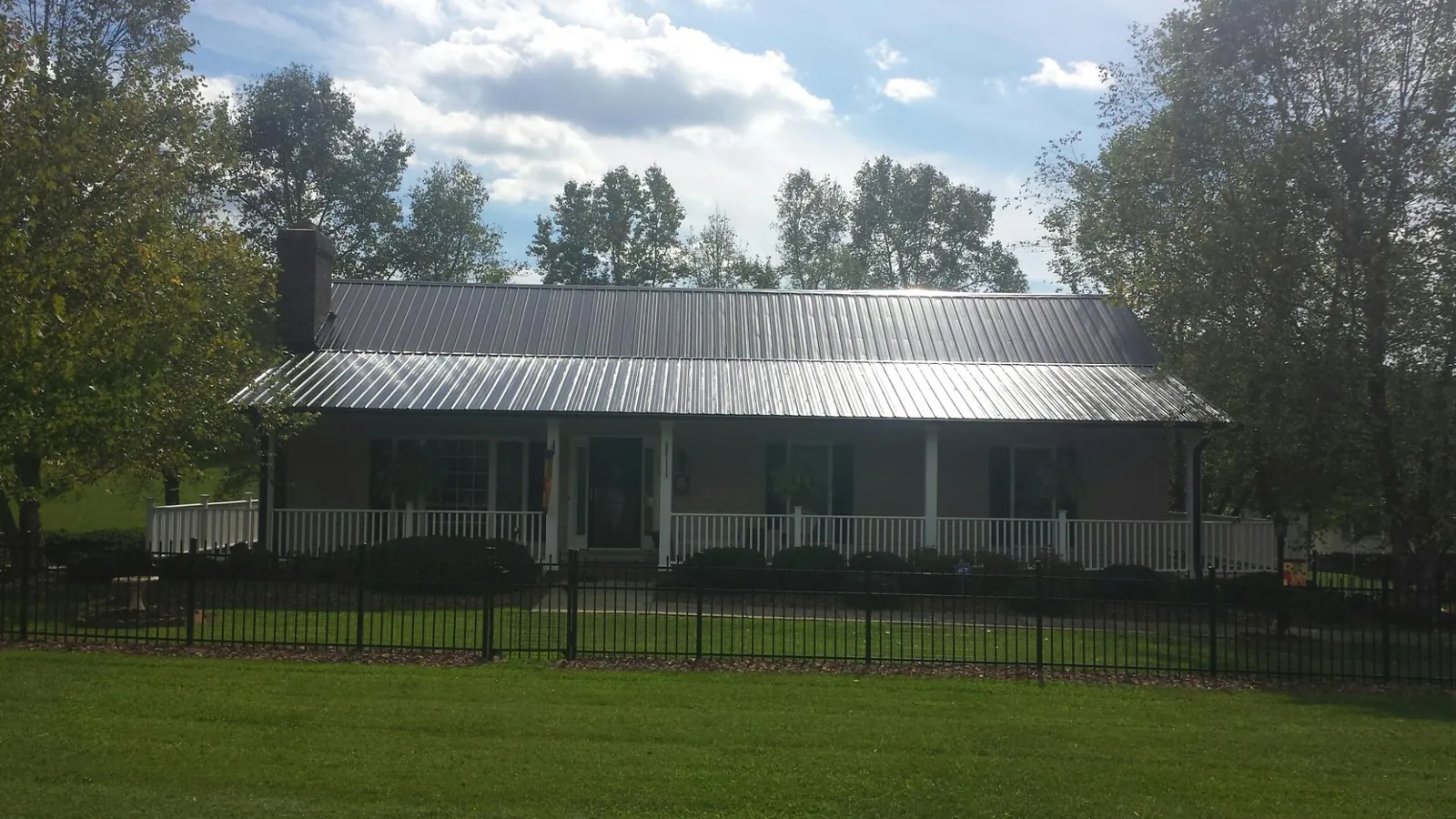 Gray metal roof on a brick ranch with a full width front porch — Gutter Guard Installation work by our crew in Amanda Park