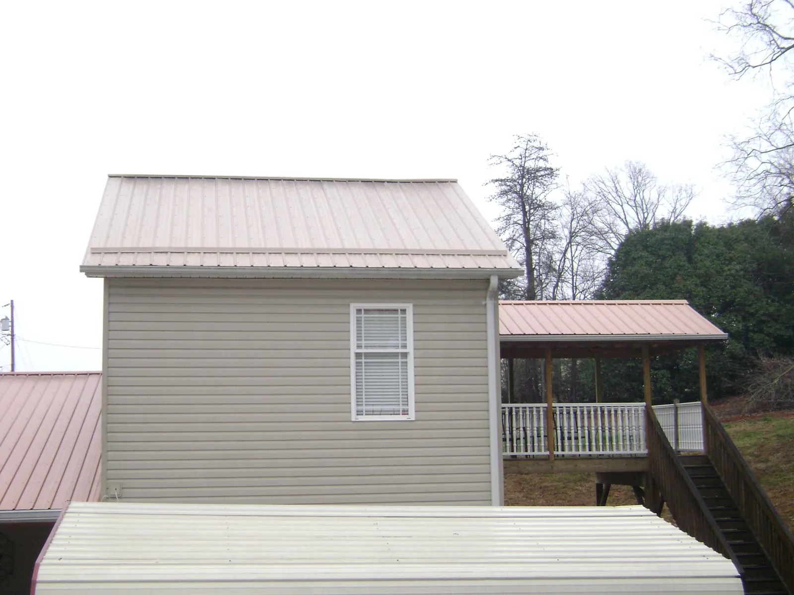 Tan metal roofs on a two story addition and attached porch, from a Roof Replacement job in Amanda Park