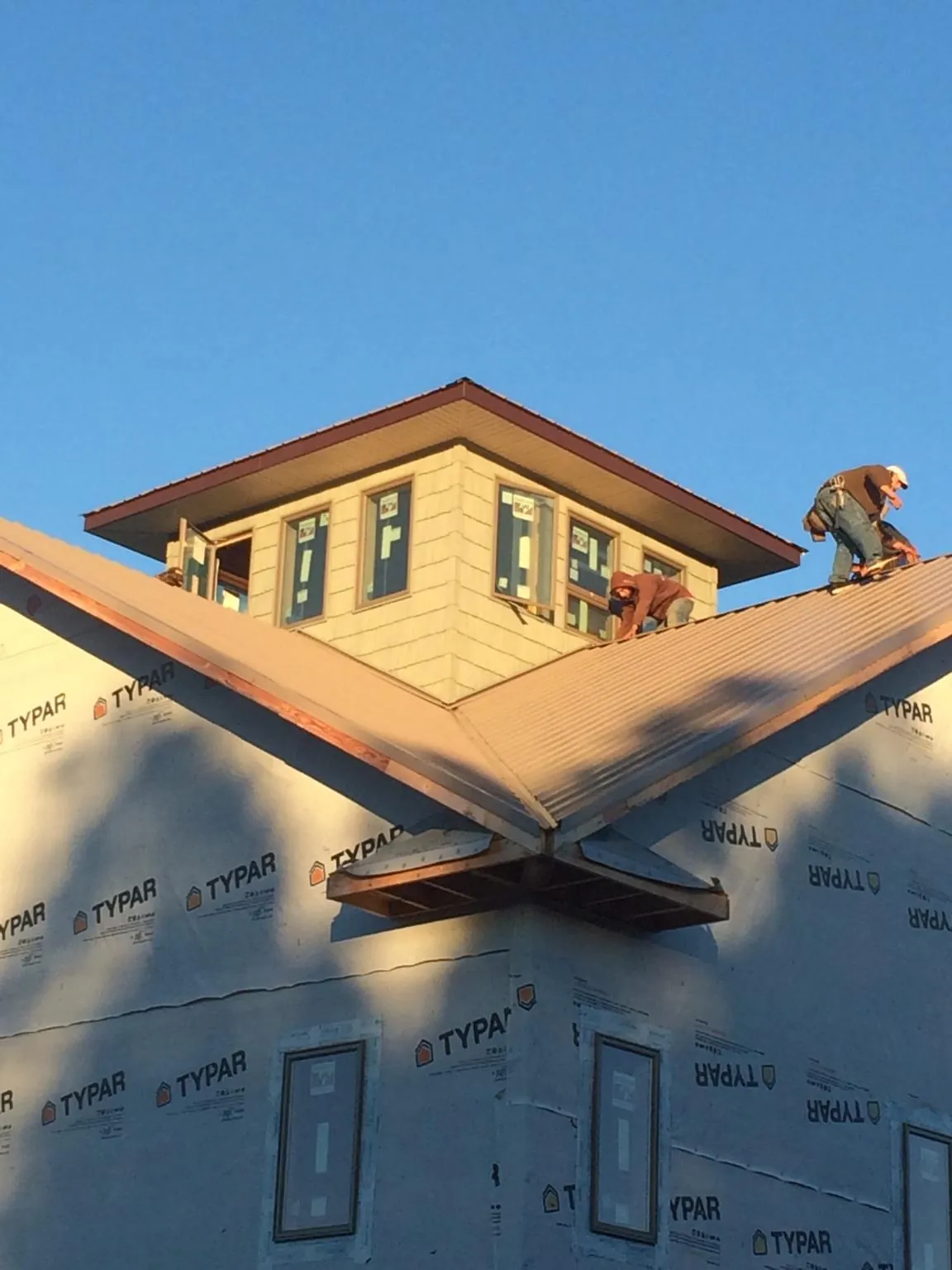 Roofers working around a rooftop cupola on a new metal roof at sunset — Roof Waterproofing in Amanda Park by Roofing Brothers